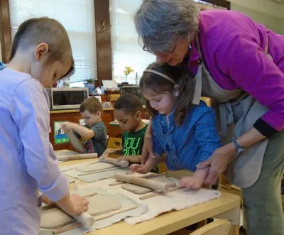 teacher with two students rolling out clay