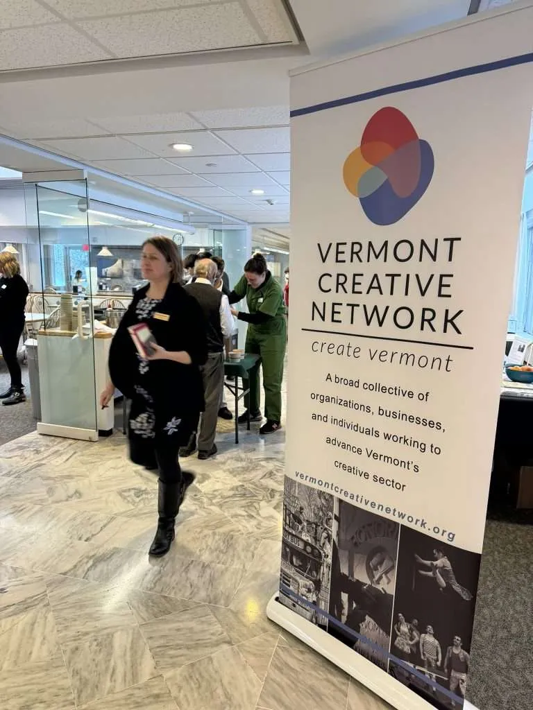 woman walking past Vermont Creative Network sign